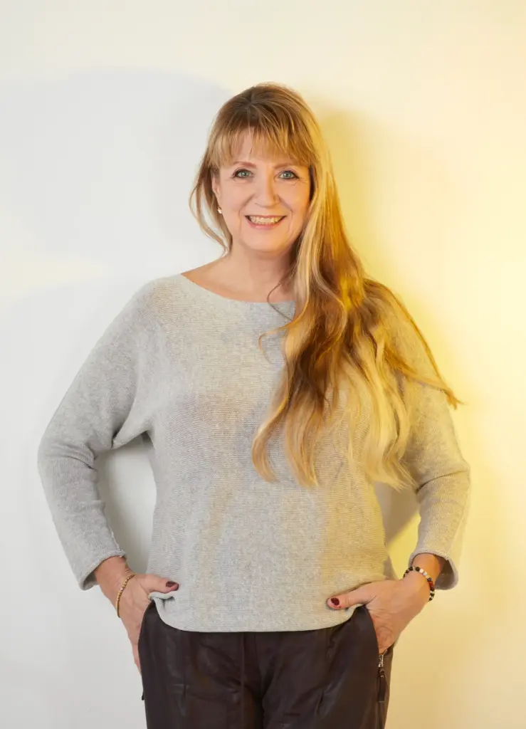 Portrait von Karolin Ewald im grauen Pullover mit angewinkelten Armen – Unterstützt auf dem Weg zur Selbstführung und Selbstachtung