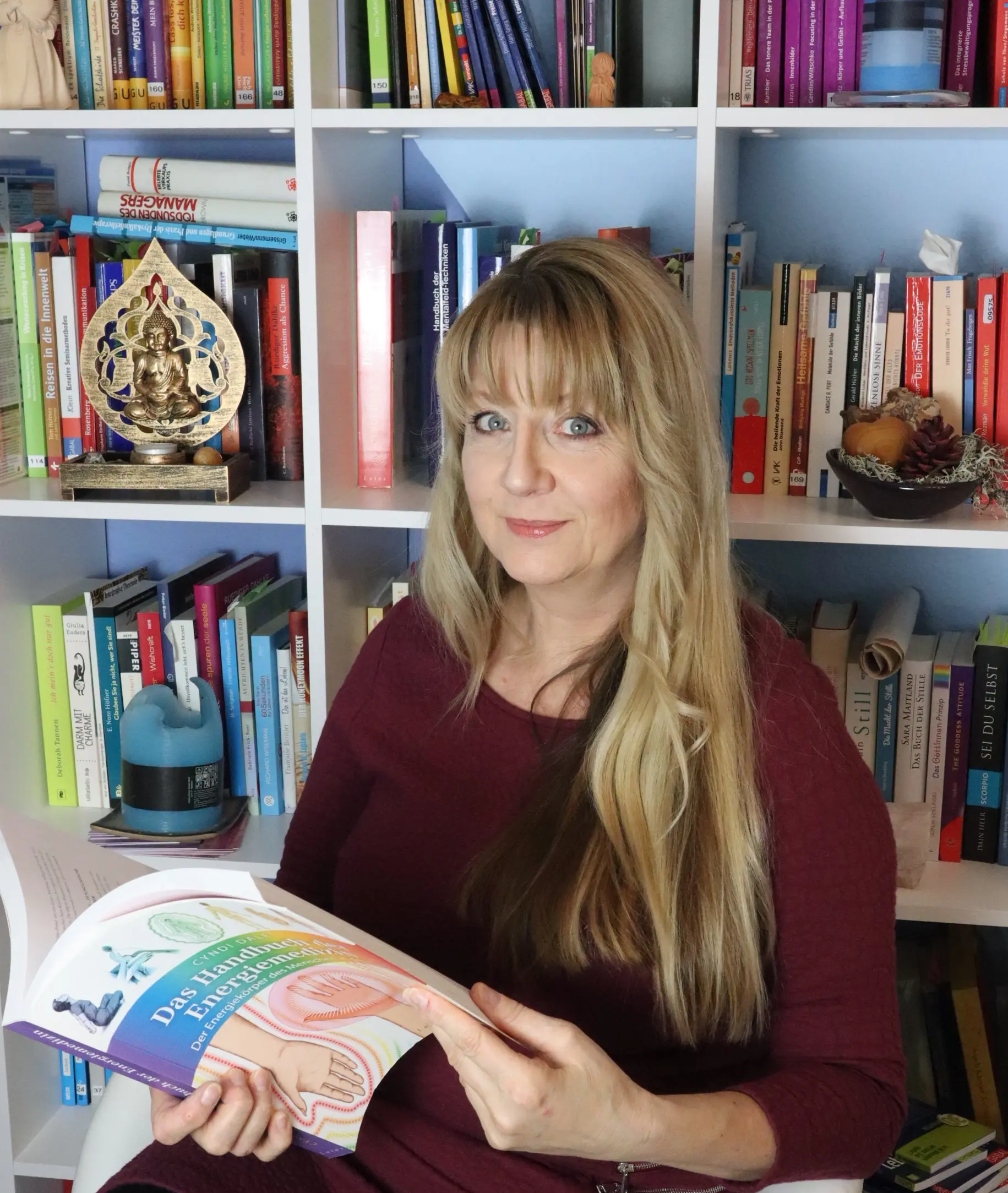 Portrait von Karolin Ewald, Psychotherapeutin und Autorin des Workbooks Nein sagen, im dunkelroten Pullover vor einem Bücherregal