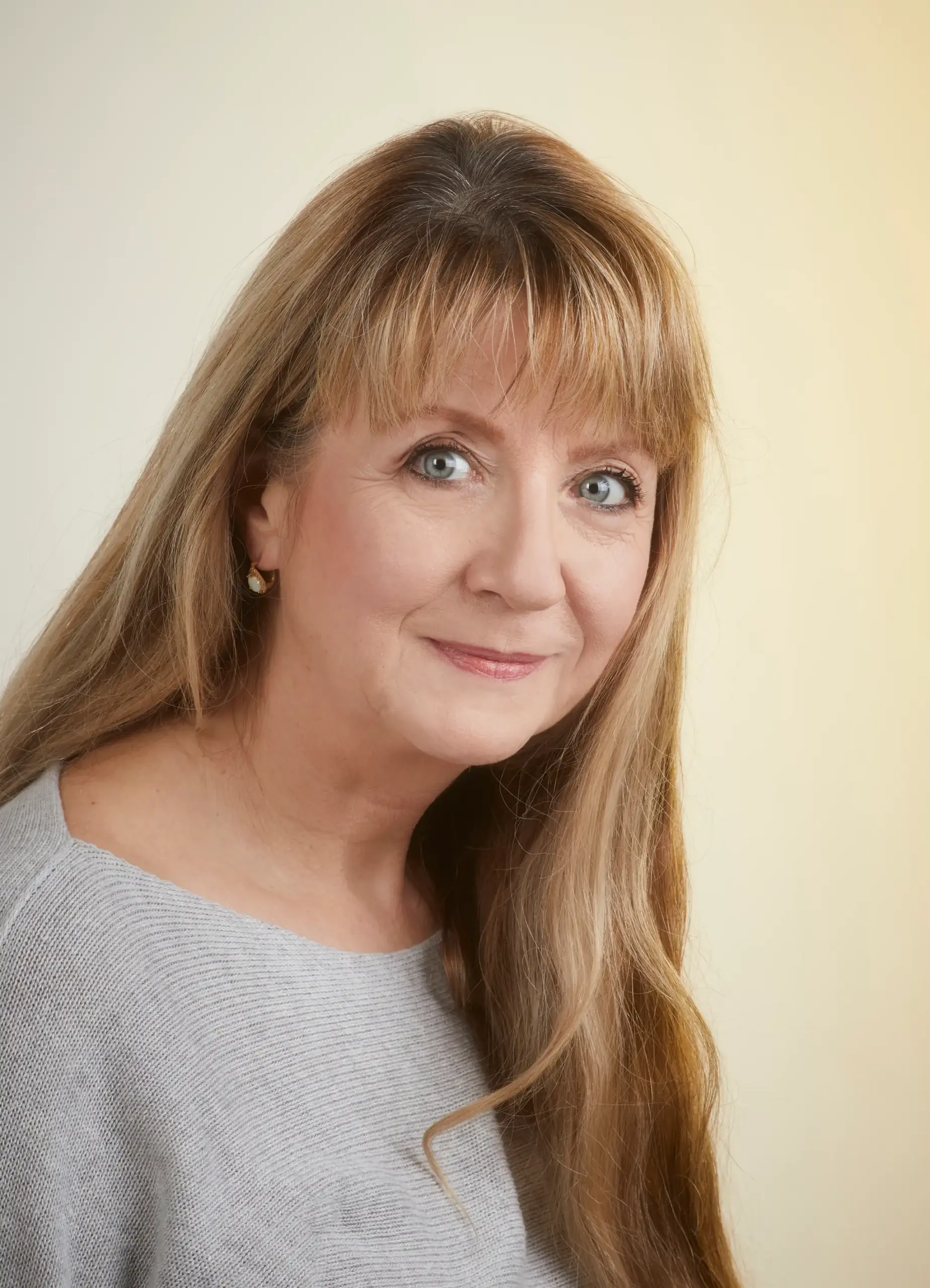 Portrait von Karolin Ewald im grauen Pullover vor einer hellgelben Wand